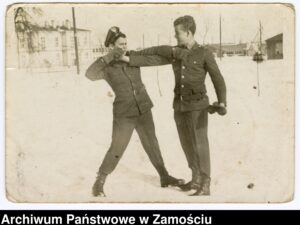 Żołnierze w trakcie ćwiczeń walki wręcz. W tle budynki koszar Technicznej Szkoły Wojsk Lotniczych w Zamościu. Zamość, styczeń 1962 r.; autor N.N.