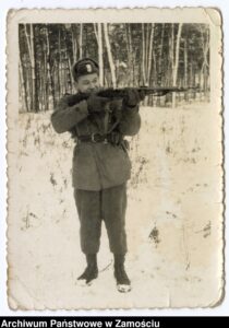 Żołnierz mierzący z karabinu podczas ćwiczeń w terenie. Sitaniec-Wolica, 1962 r.; autor N.N. Na rewersie dedykacja: "Na Wieczną pamiątkę ofiaruję swą podobiznę. Zbyszek, "Cześkowi", 29.07.1962 r. Lublin szpital"